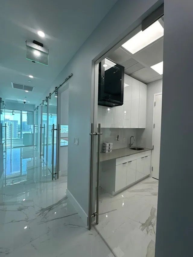 A kitchen with white cabinets and a tv on the wall