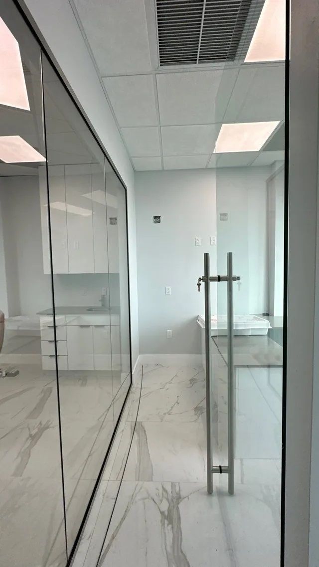 A hallway with a glass wall and a marble floor.