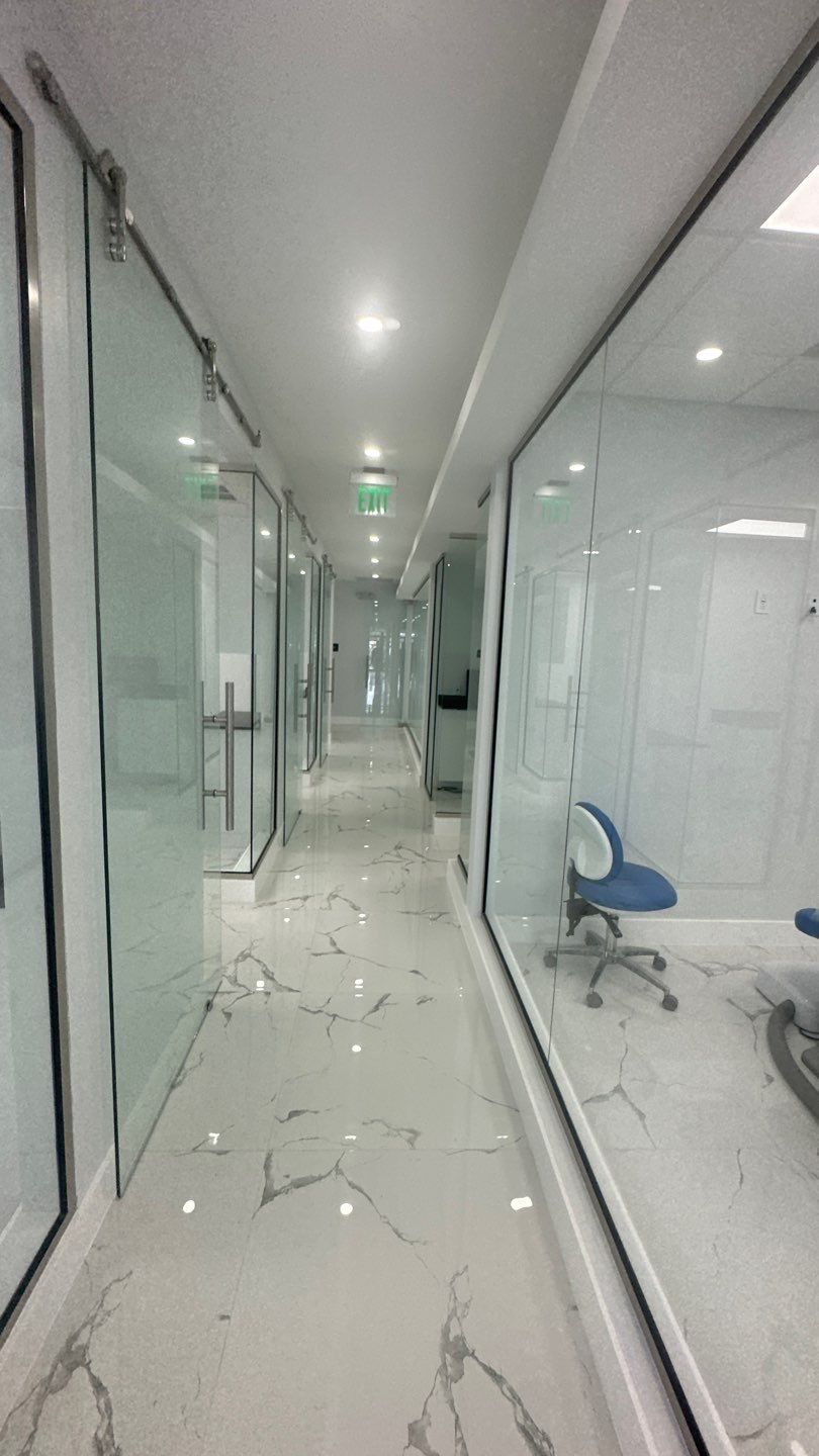 A long hallway with glass walls and a blue chair.