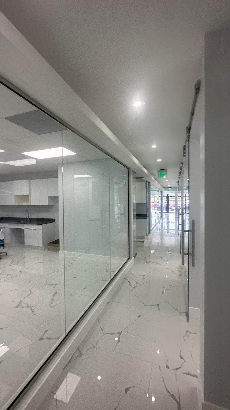 A long hallway with marble floors and glass walls in a building.