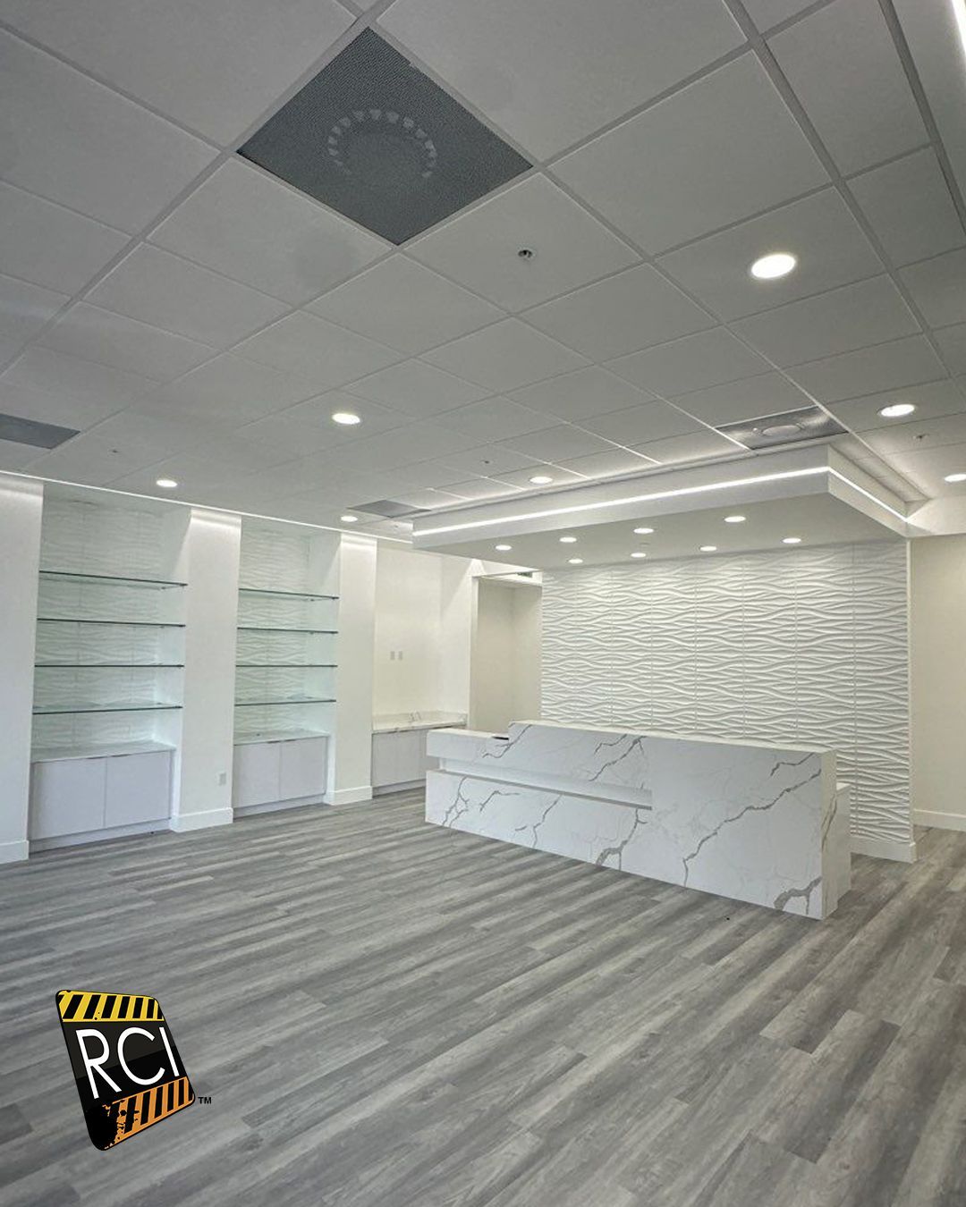 A large empty room with a reception desk and shelves.