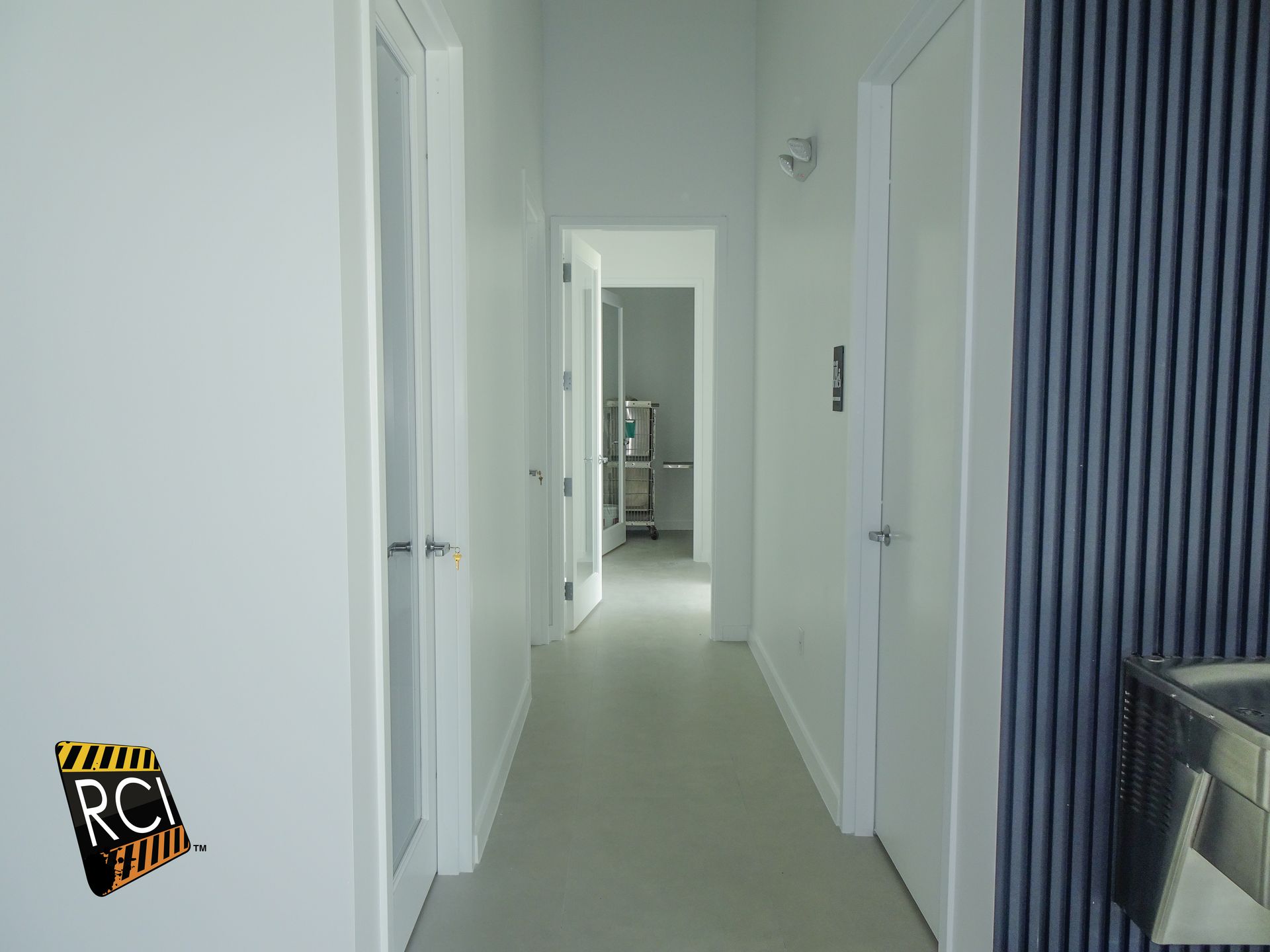 A long hallway with white walls and blue stripes on the wall