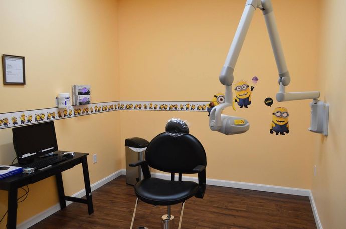 A young boy is sitting in a dental chair while a dentist examines his teeth.