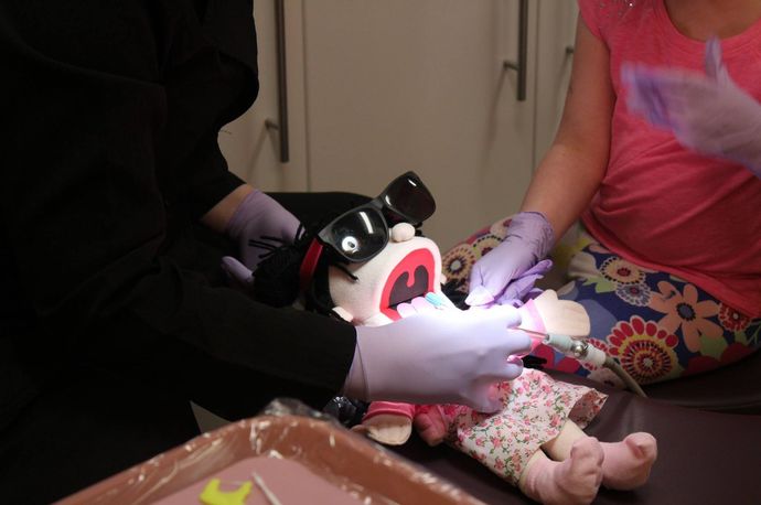 A young boy is sitting in a dental chair while a dentist examines his teeth.