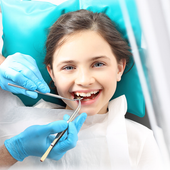 A little girl is getting her teeth examined by a dentist