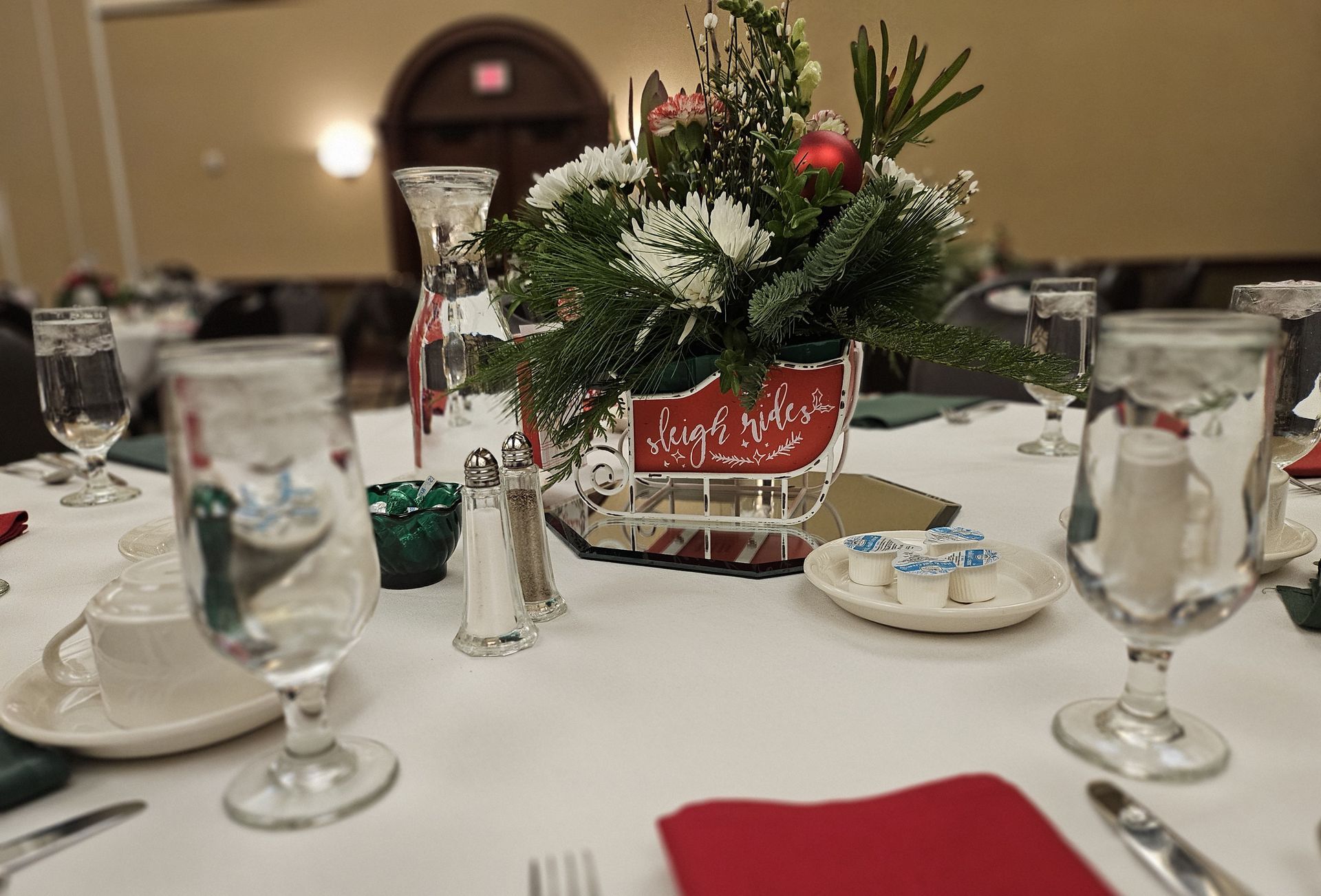 A table set for a christmas dinner with a vase of flowers on it
