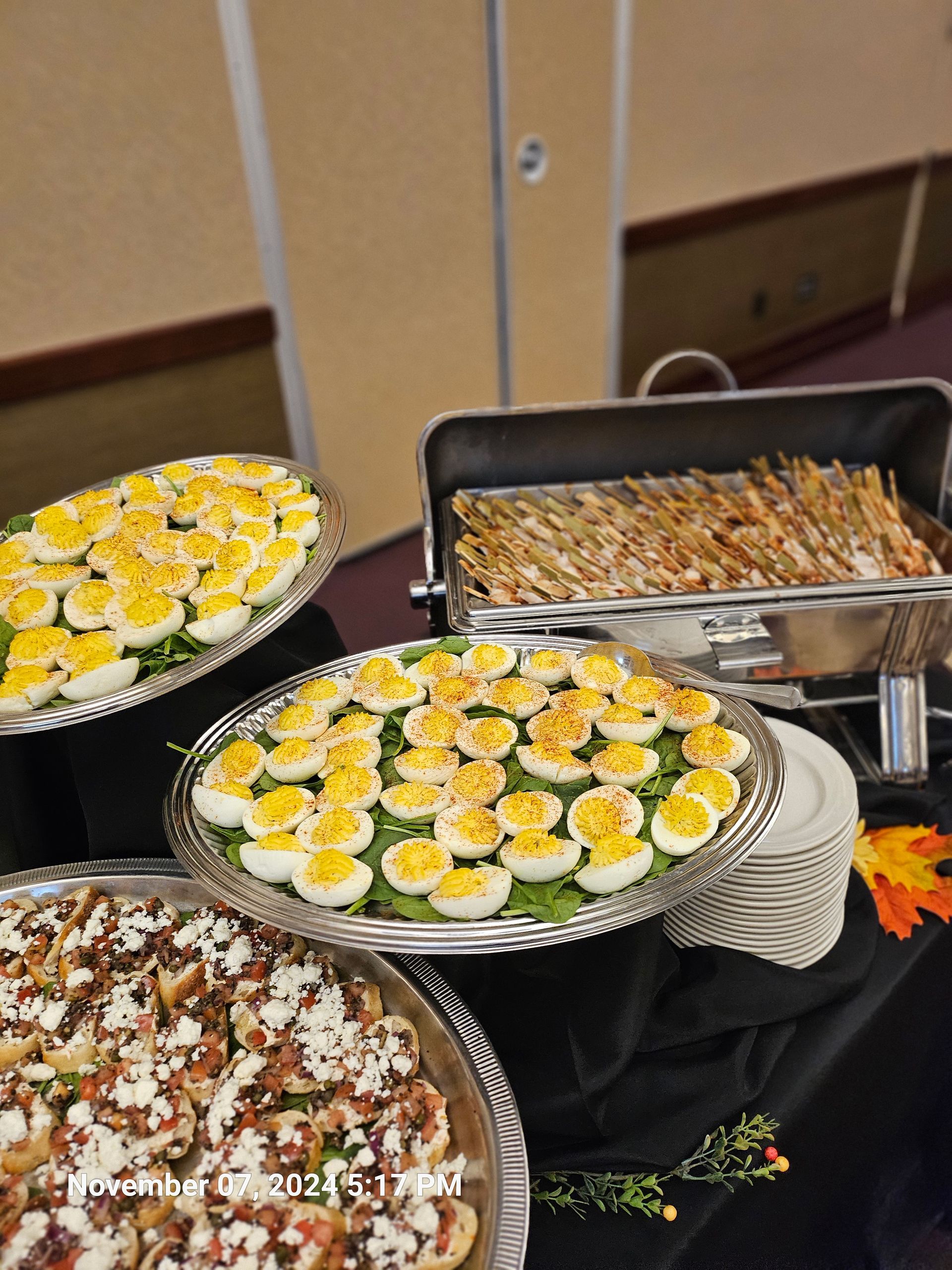 A buffet table with plates of food including hard boiled eggs and shrimp.