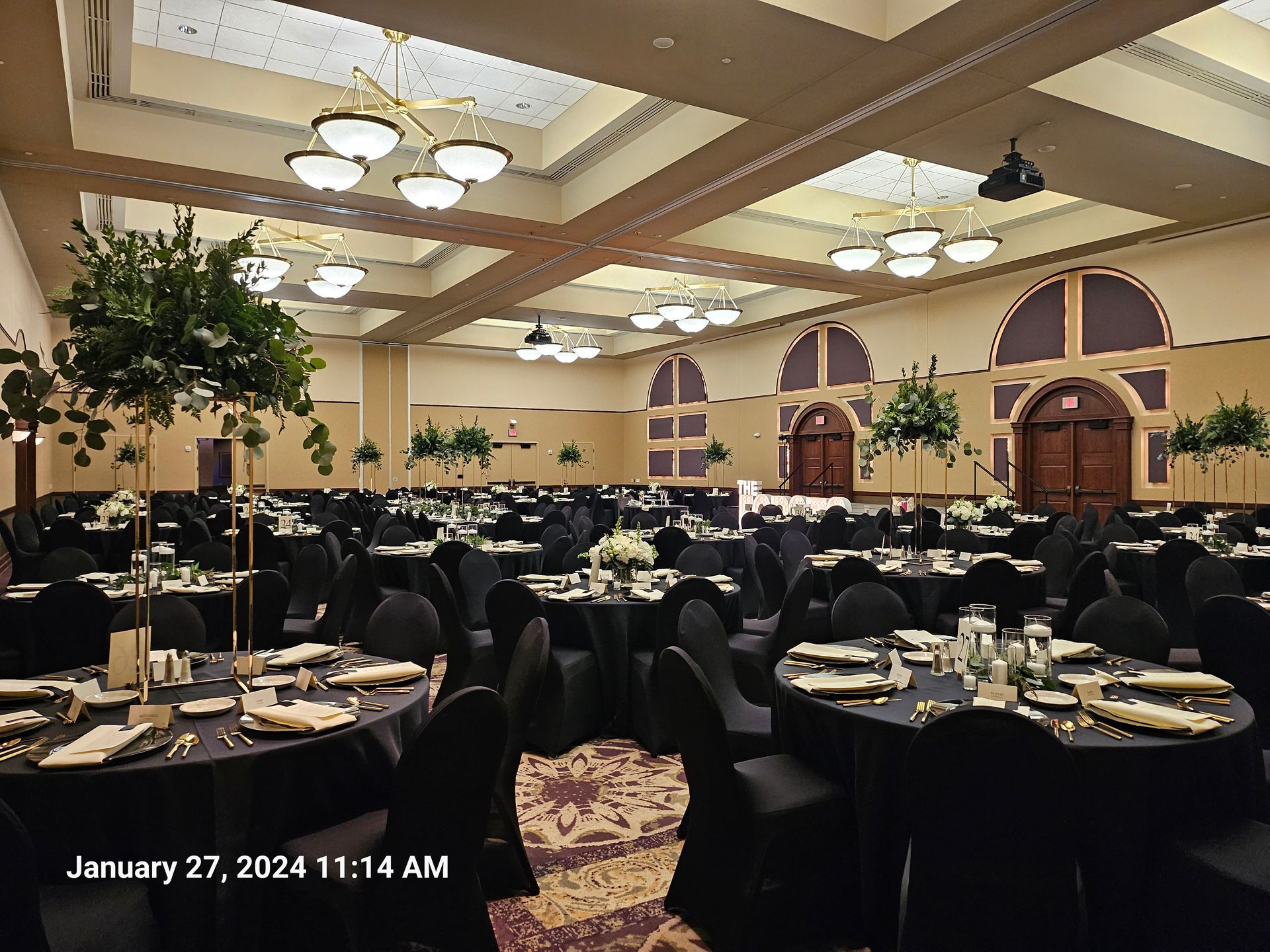 A large room with tables and chairs set up for a wedding reception