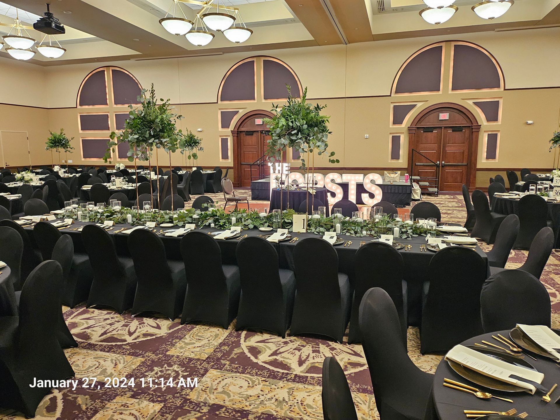 A large room with tables and chairs set up for a wedding reception