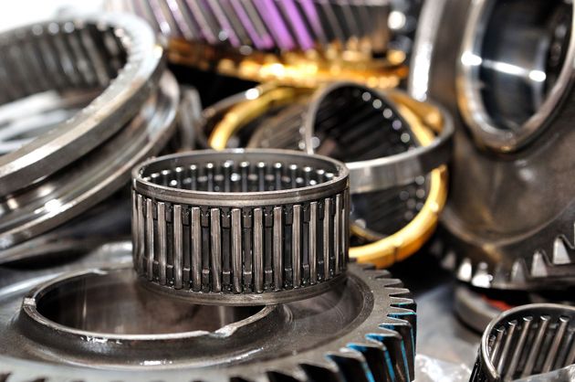 Metal gears and bearings stacked together, with silver, gold, and purple components visible