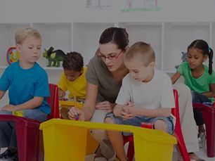 A teacher is playing with a group of children in a classroom.