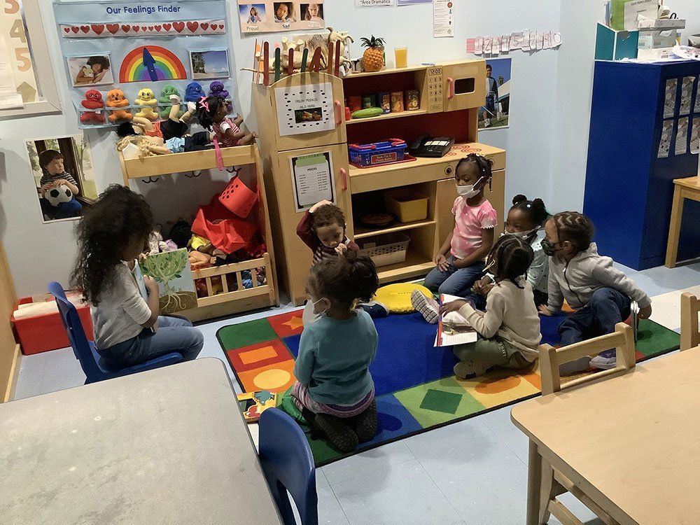 A group of children are sitting on the floor in a classroom