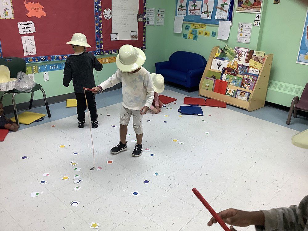 A group of children wearing hats are playing in a classroom