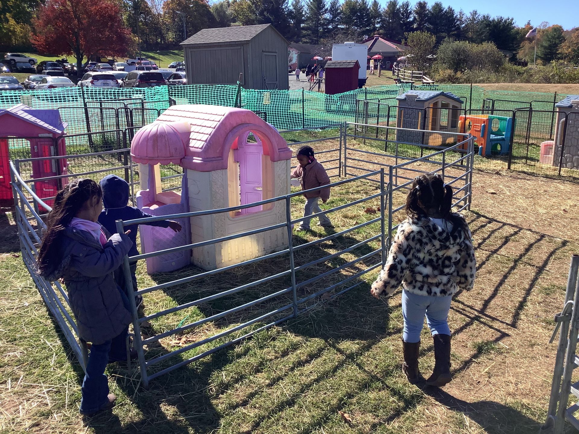 A group of children are playing in a playground with a pink playhouse