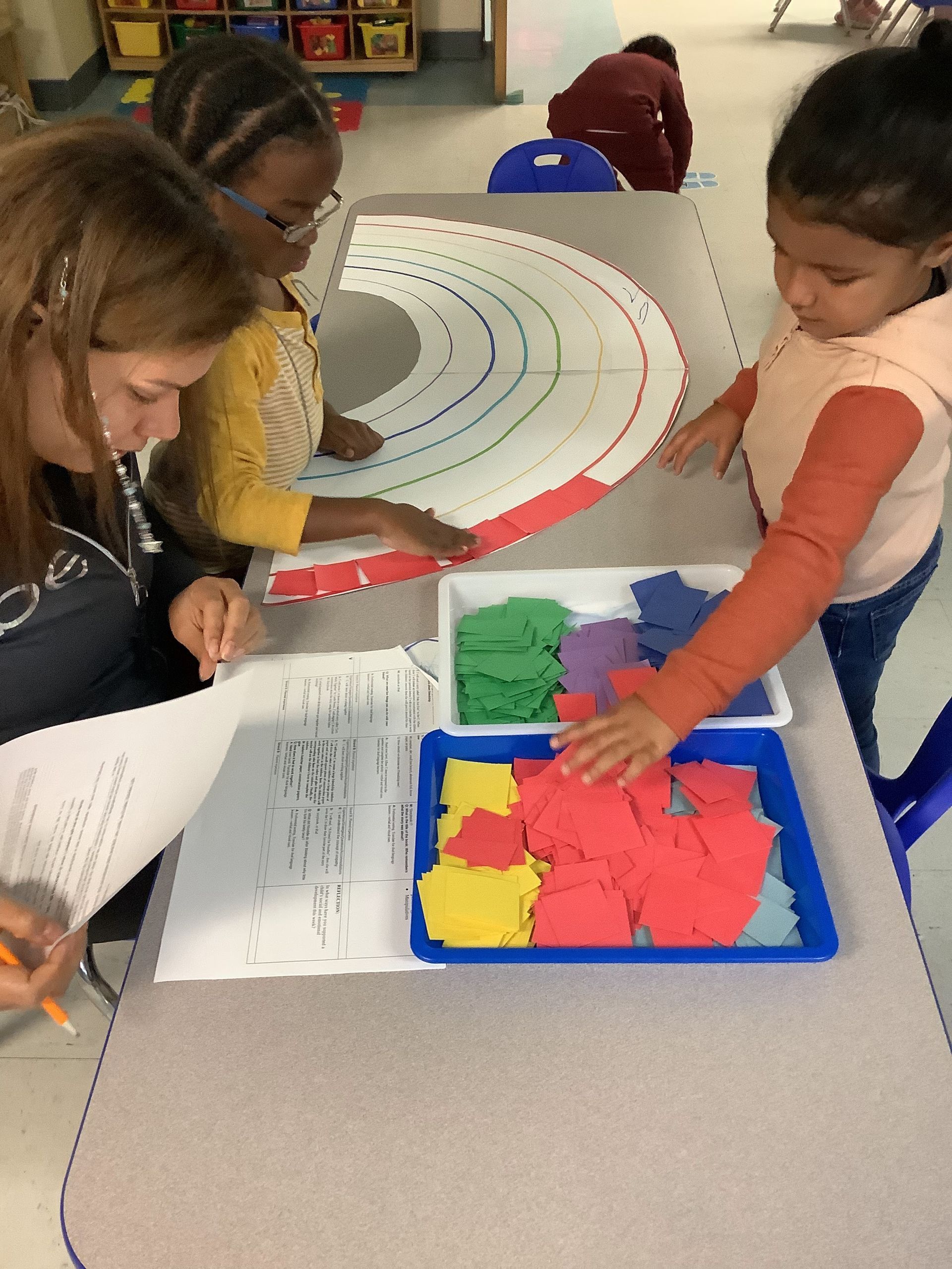 A group of children are sitting at a table playing with a rainbow