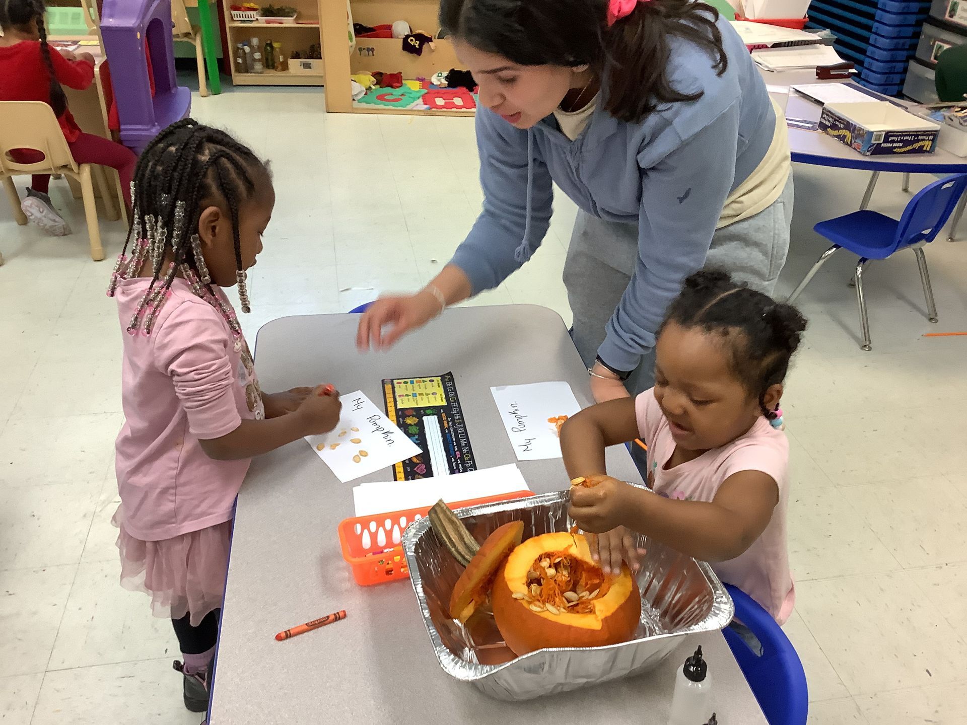 A woman is teaching two little girls how to carve a pumpkin