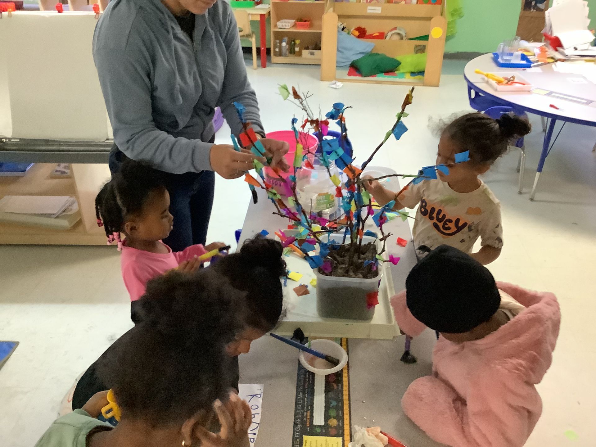 A group of children are sitting around a table playing with toys
