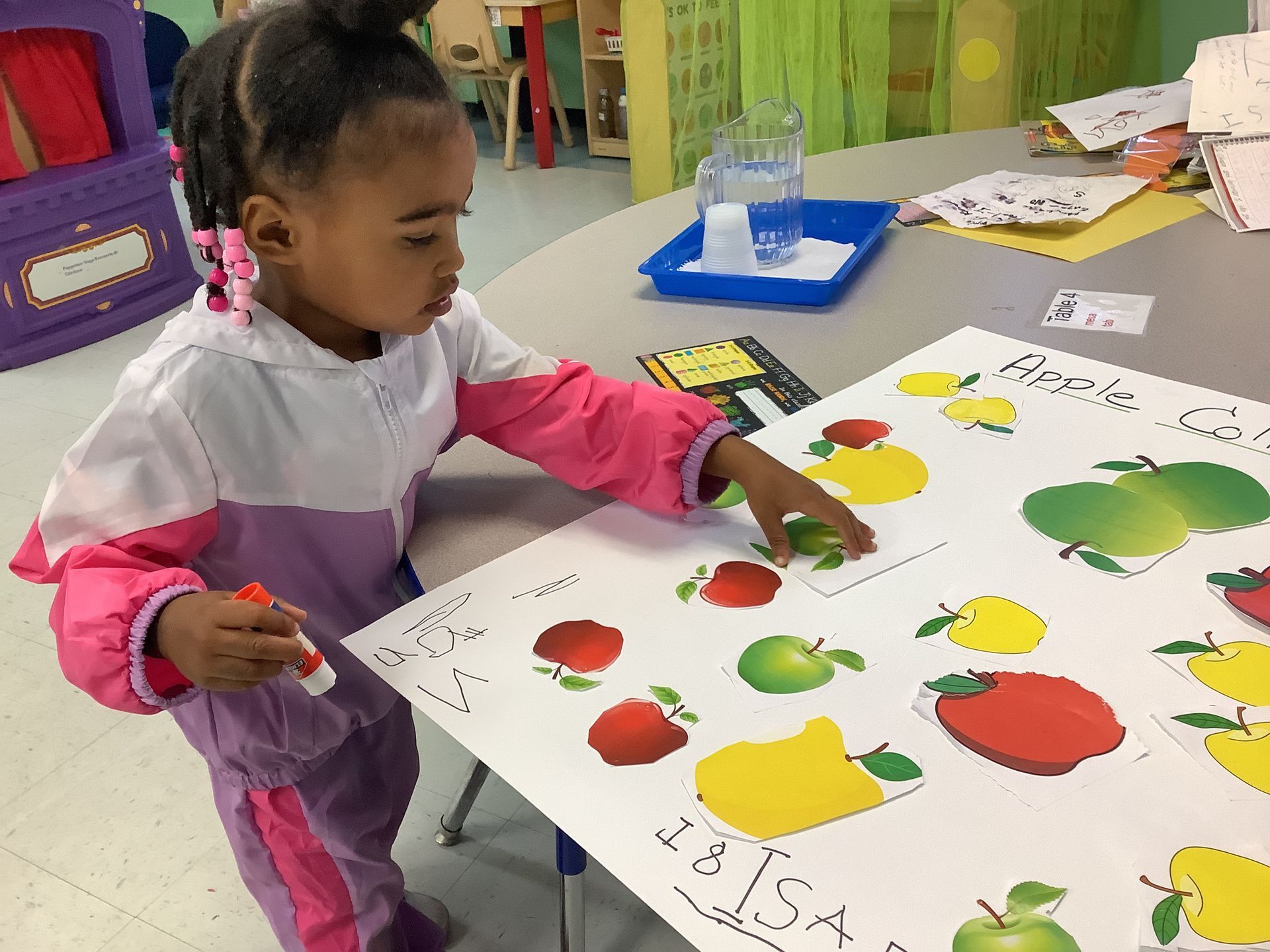 A little girl is pointing at an apple on a poster
