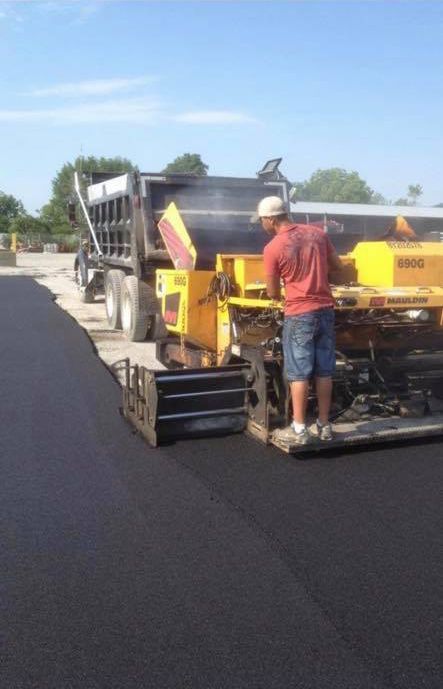 A man is standing next to a machine on a road.