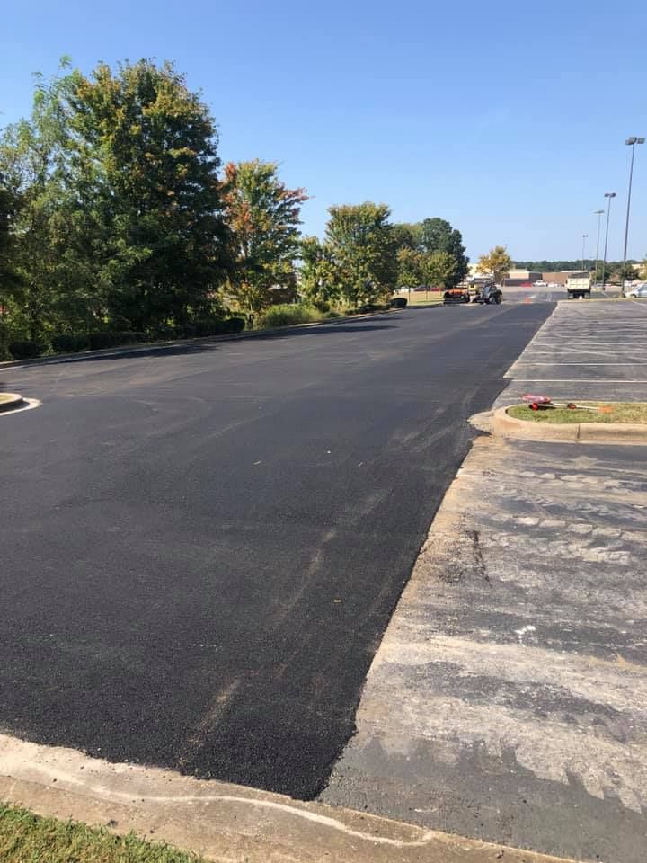 A newly paved parking lot with a lot of cars parked in it on a sunny day.
