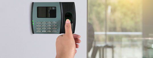 Man or woman push finger down on finger scan machine for access door security systems