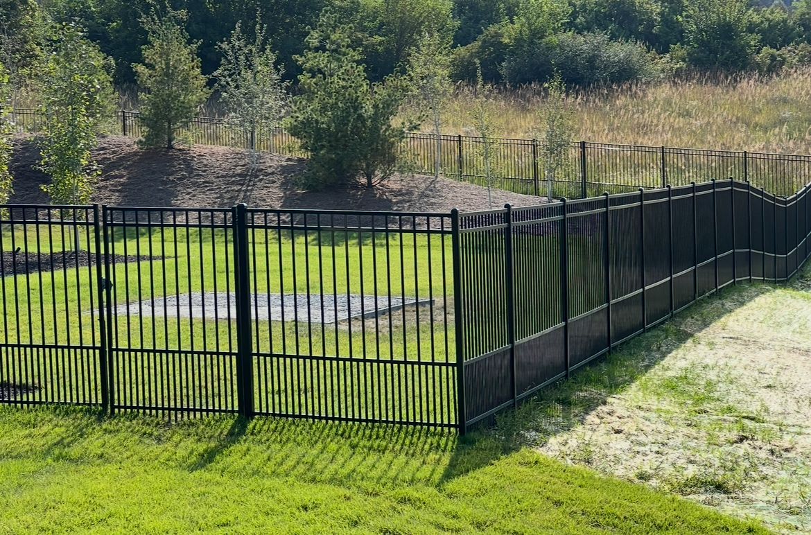 Black metal fence around a grassy backyard with a raised, covered pool area