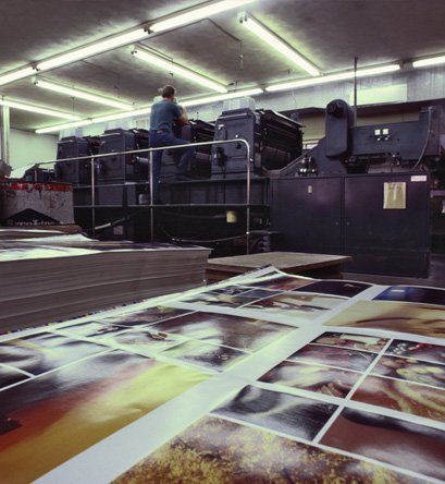 Worker in front of printing machinery with printed photos behind him