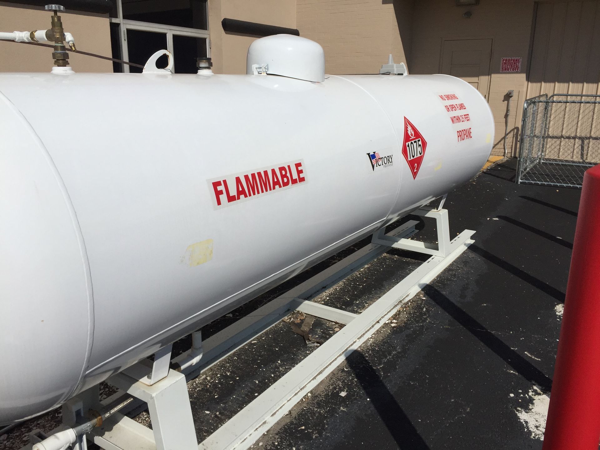 A flammable gas tank is sitting outside of a building