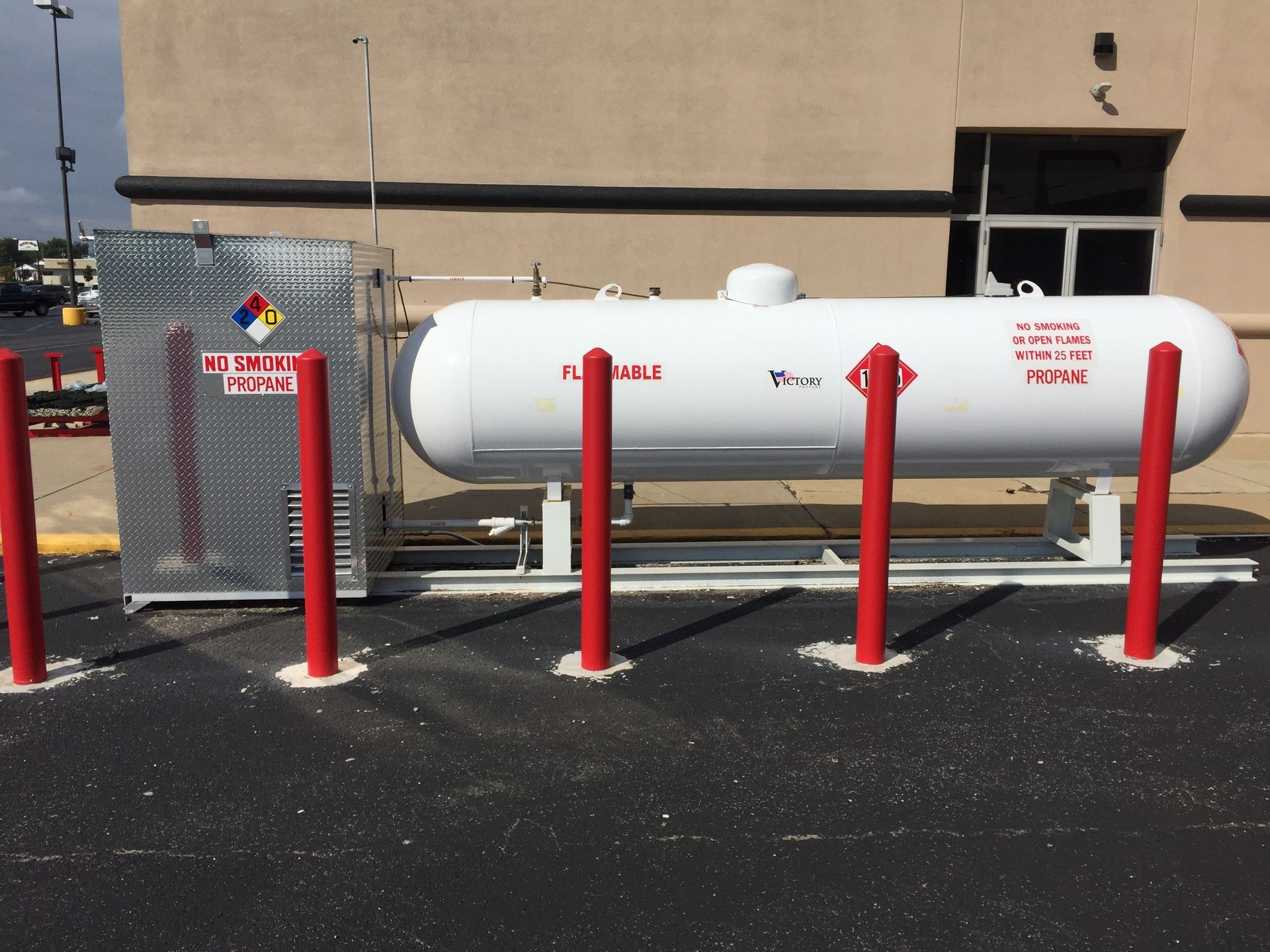 A large propane tank is surrounded by red poles