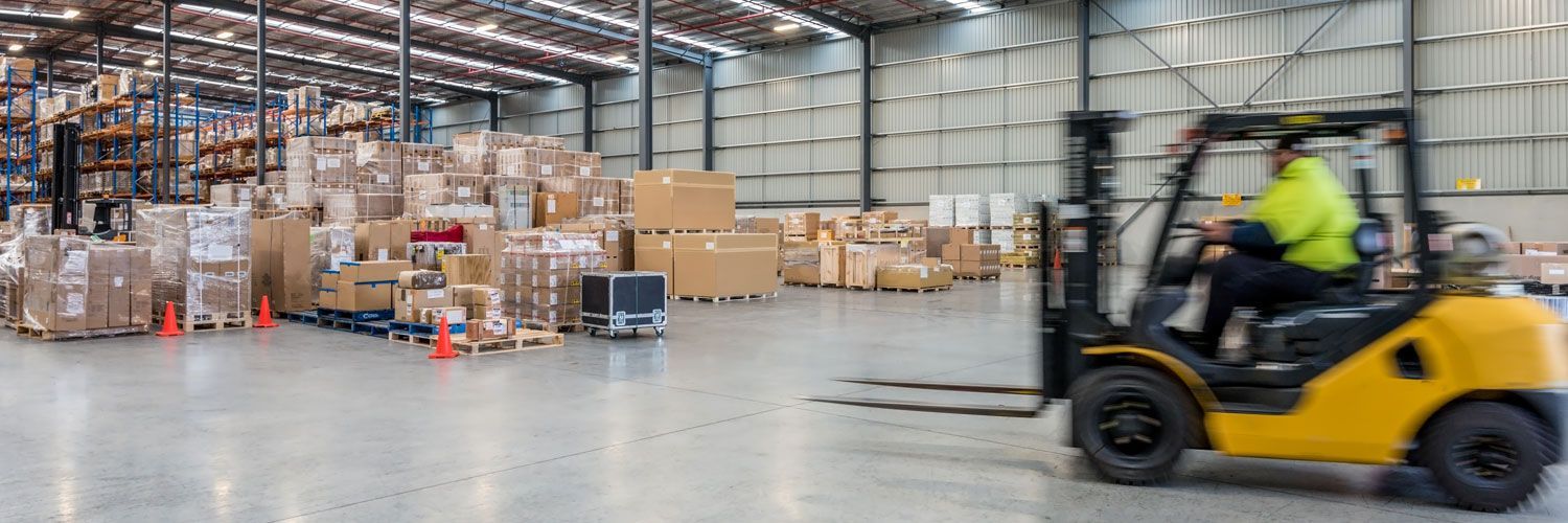 A man is driving a forklift in a warehouse.