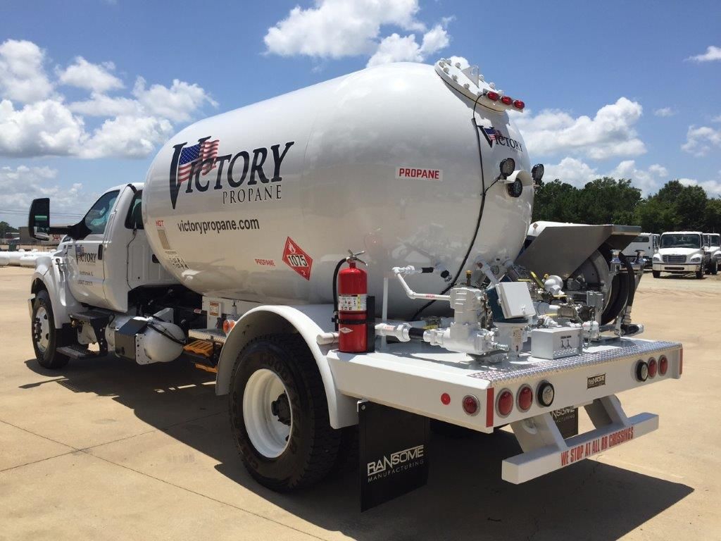 A white victory propane truck is parked on the side of the road.
