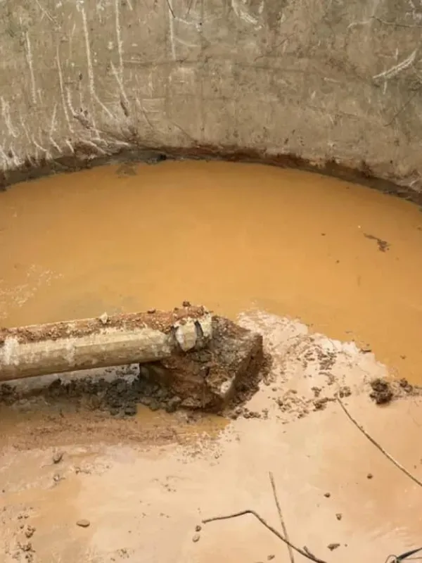 A large bucket filled with brown water and a pipe in it.