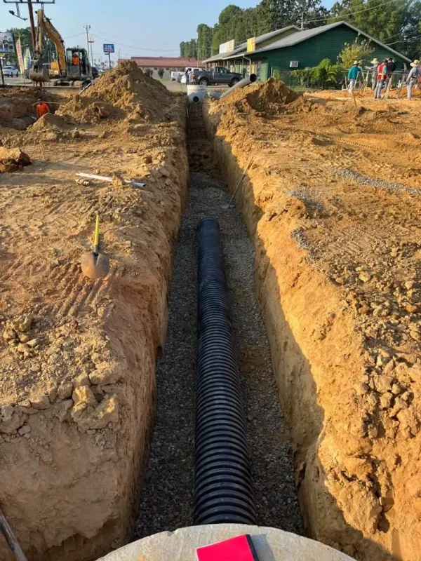 A drain pipe is being installed in a trench.