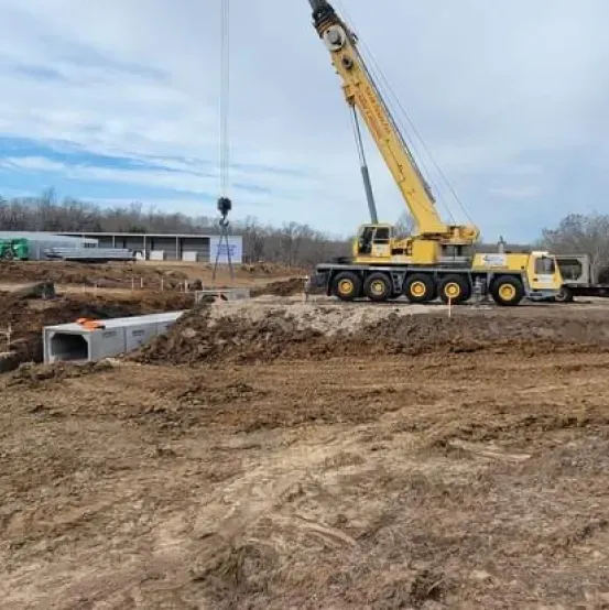 A large yellow crane is sitting in the middle of a dirt field.