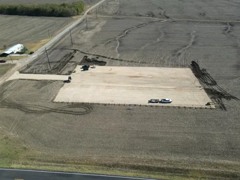 An aerial view of a large dirt field with a road in the background.