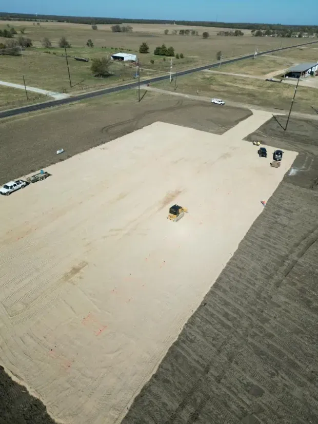 An aerial view of a large dirt field with a road going through it