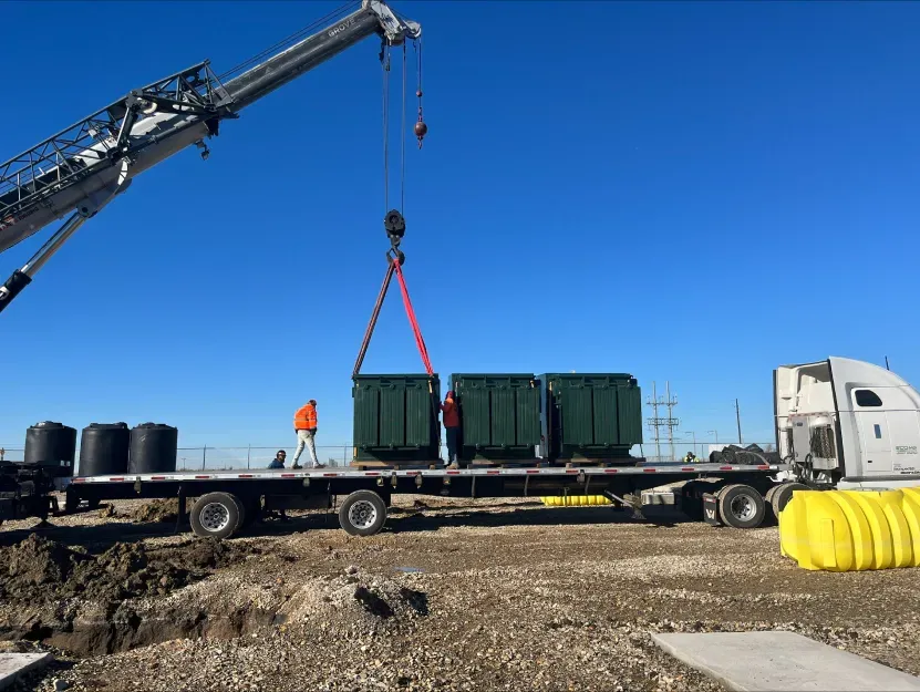 A truck is being lifted by a crane on a dirt road