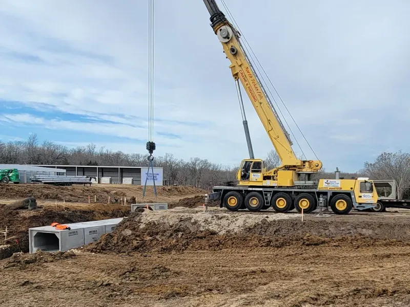 A large yellow crane is working on a construction site.