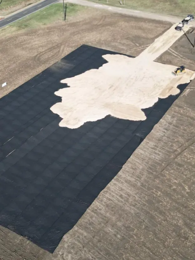 An aerial view of a large black tarp covering a dirt field