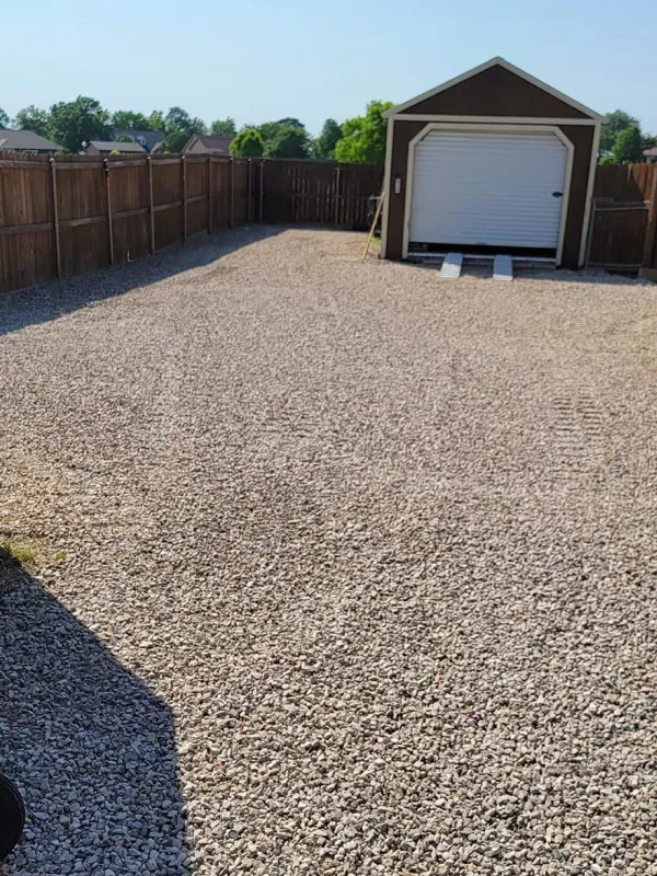 A gravel driveway with a garage in the background