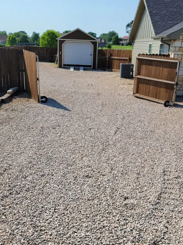 A gravel driveway leading to a garage and a house