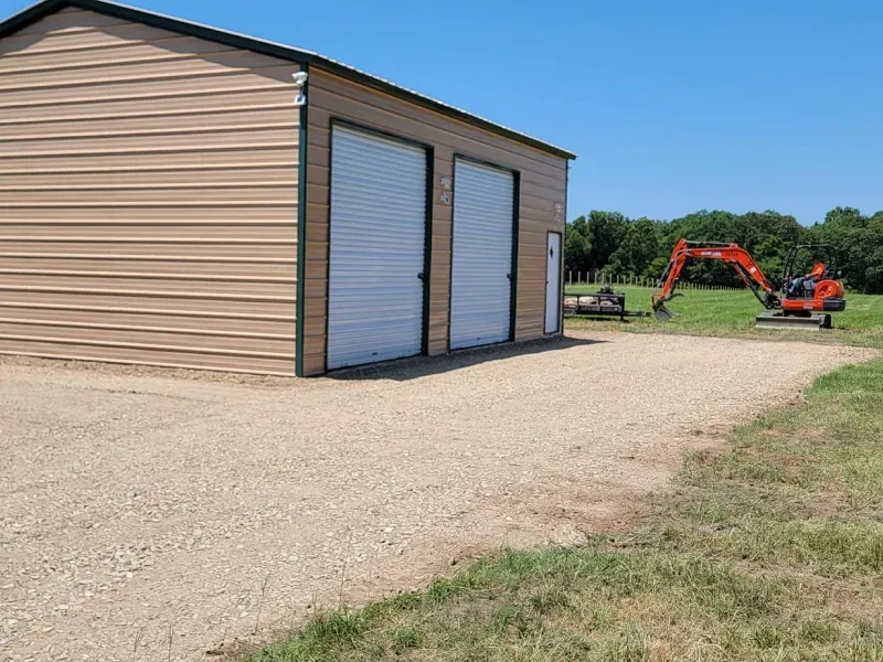 A small red excavator is parked in front of a garage.