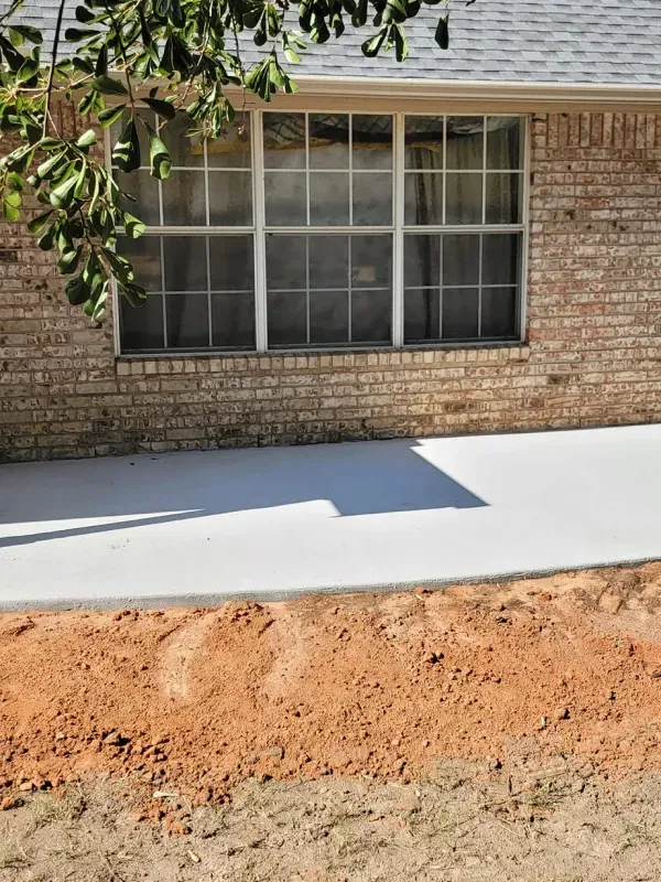 A brick house with a concrete sidewalk in front of it.