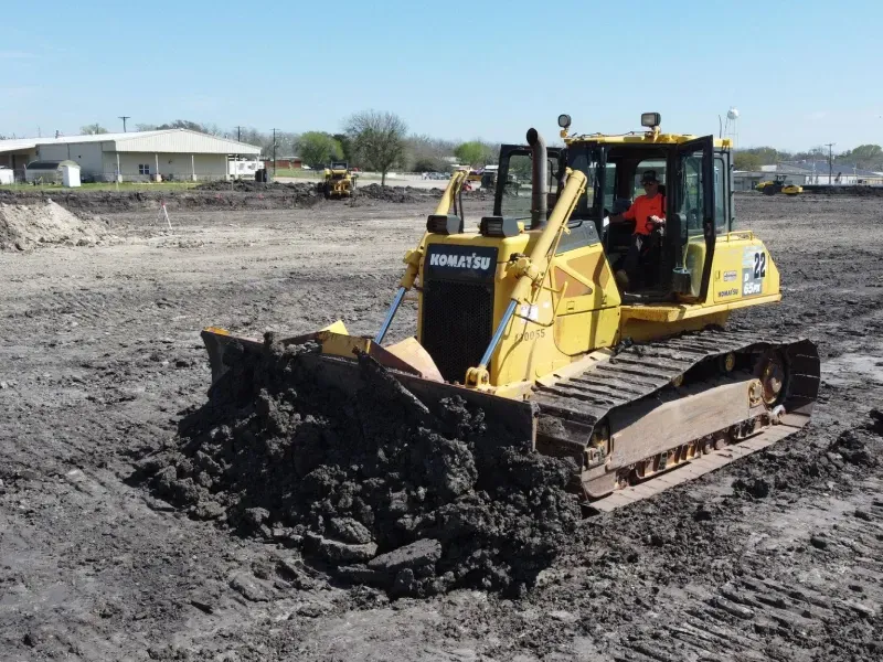 A komatsu bulldozer is driving through a muddy field