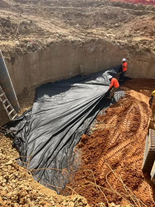 A group of construction workers are working on a large pile of dirt.