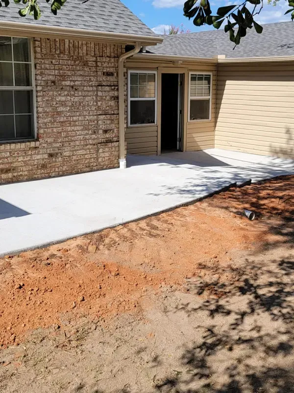 A brick house with a concrete walkway in front of it.