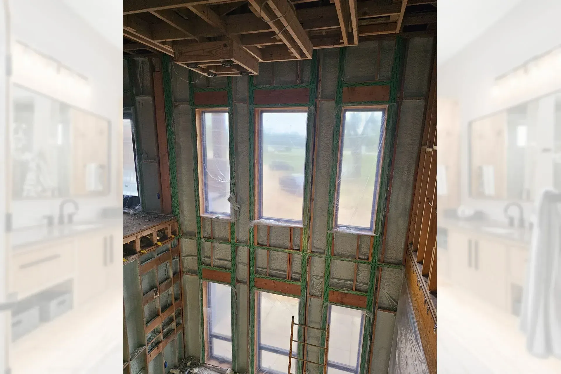 Interior construction view with tall windows, exposed framing, and unfinished walls as light fills the space.