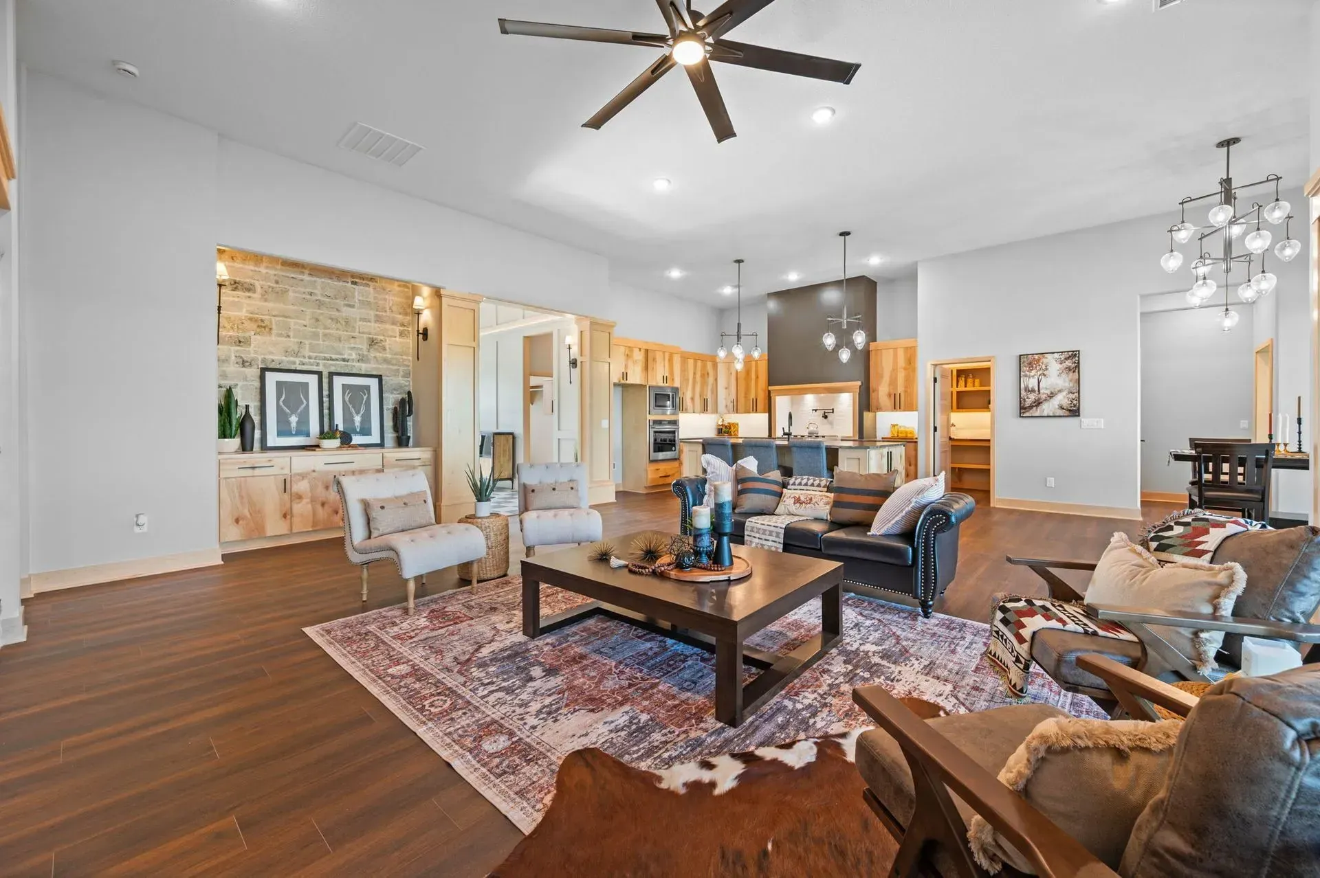 Spacious living room with vaulted ceiling, ceiling fan, sectional sofa, coffee table, and hardwood floors