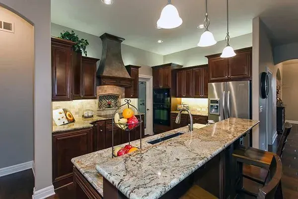 Modern kitchen with granite island, dark wood cabinets, stainless appliances, and pendant lights