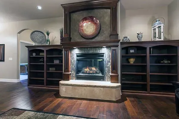 Living room fireplace with dark wood built-ins and a mantel, centered on a stone hearth with a clock above
